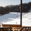 View from terrace to snowy ski slope with skiers and gondolas
