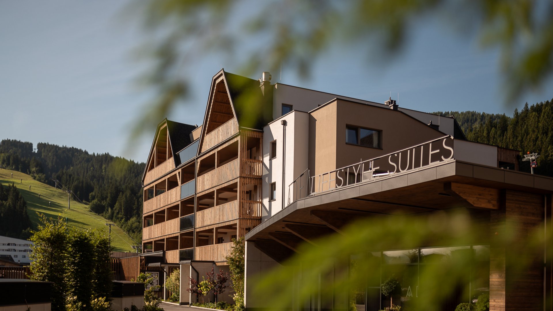 Modernes Hotel mit Holzbalkonen und Bergblick an sonnigem Tag