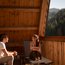 Couple relaxing and talking on wooden balcony with mountain view